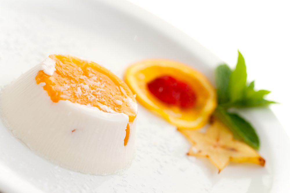 Italian dessert panna cotta on white plate decorated with coconu